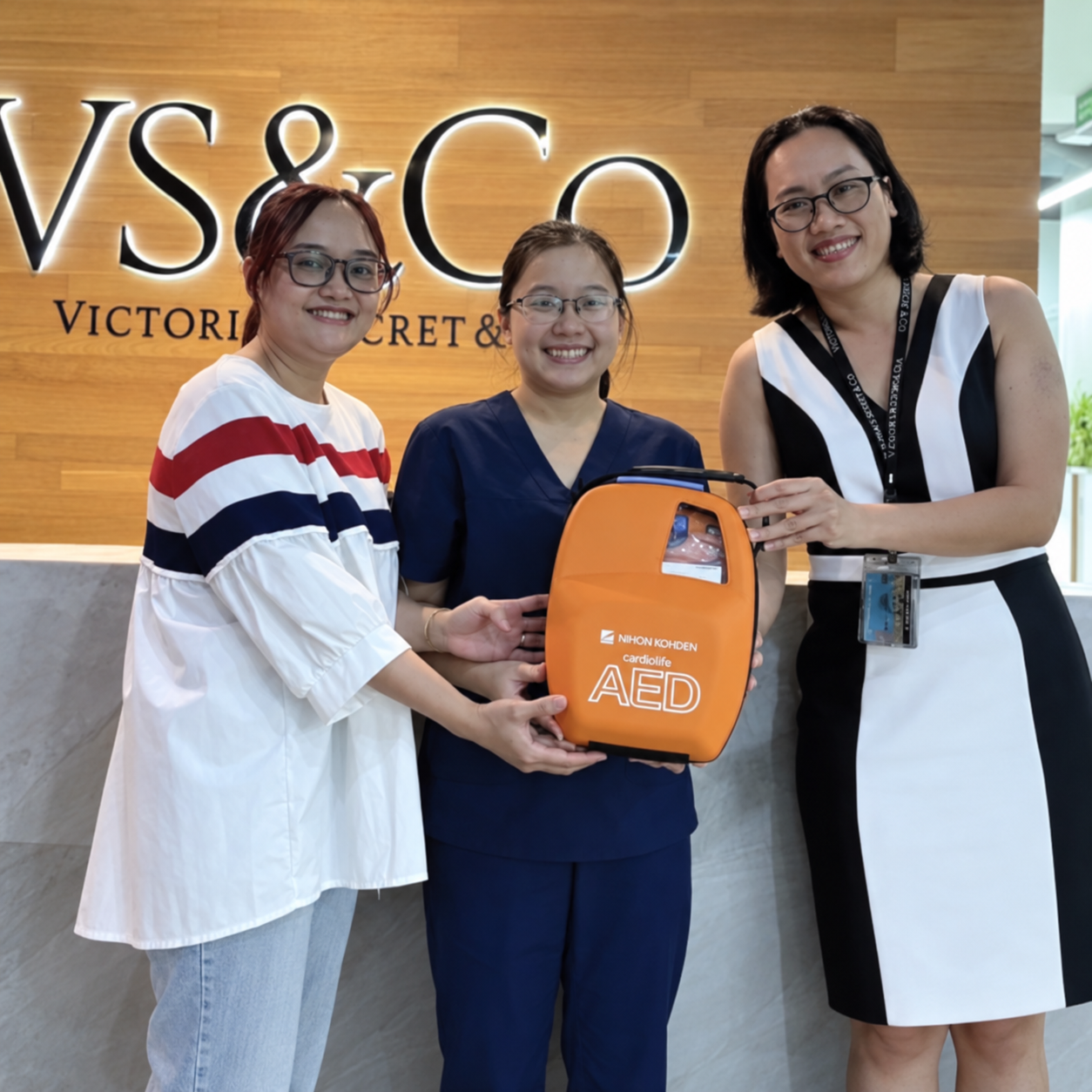Smiling-Team-with-Orange-AED-at-Reception